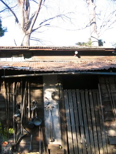 壁に農機具がかかった木造小屋