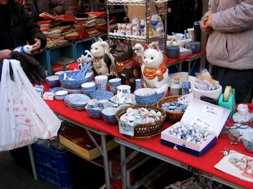 食器の屋台の中心で3匹の招き猫が手を上げている