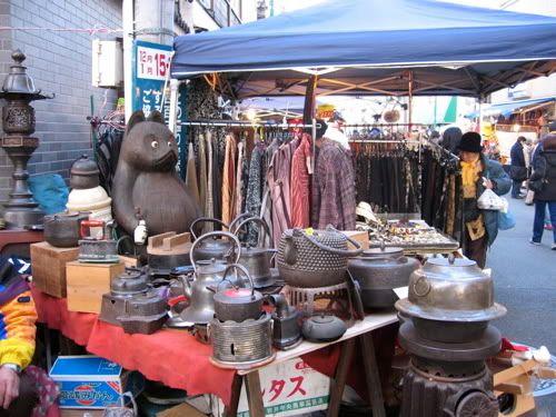 やかん売り場の奥で目を見開く木彫りのタヌキ