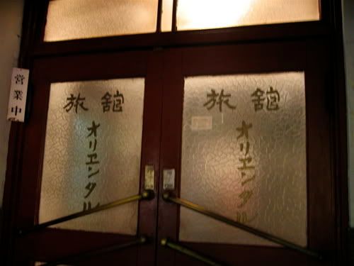 木製の両開き扉のガラス部分に手描きで「旅館オリエンタル」